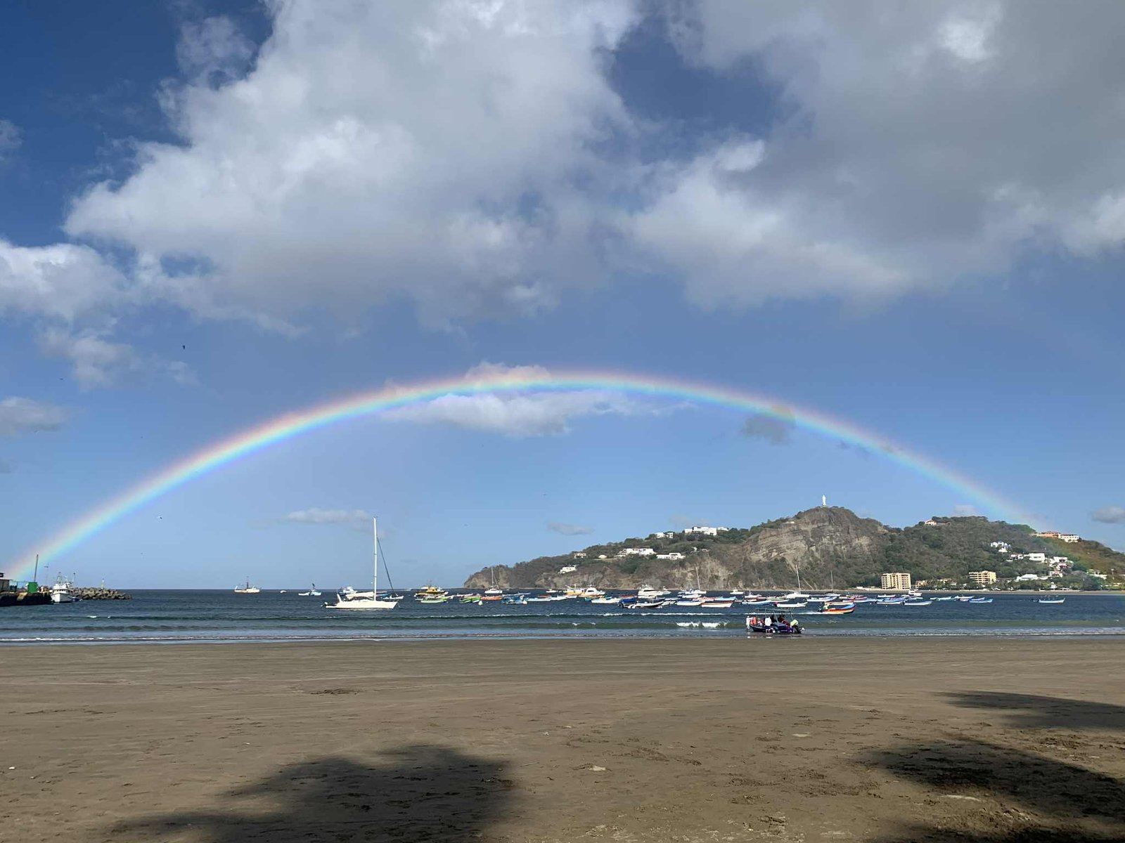 Rainbow in a cloudy blue sky over San Juan del Sur Bay, boats in the ocean