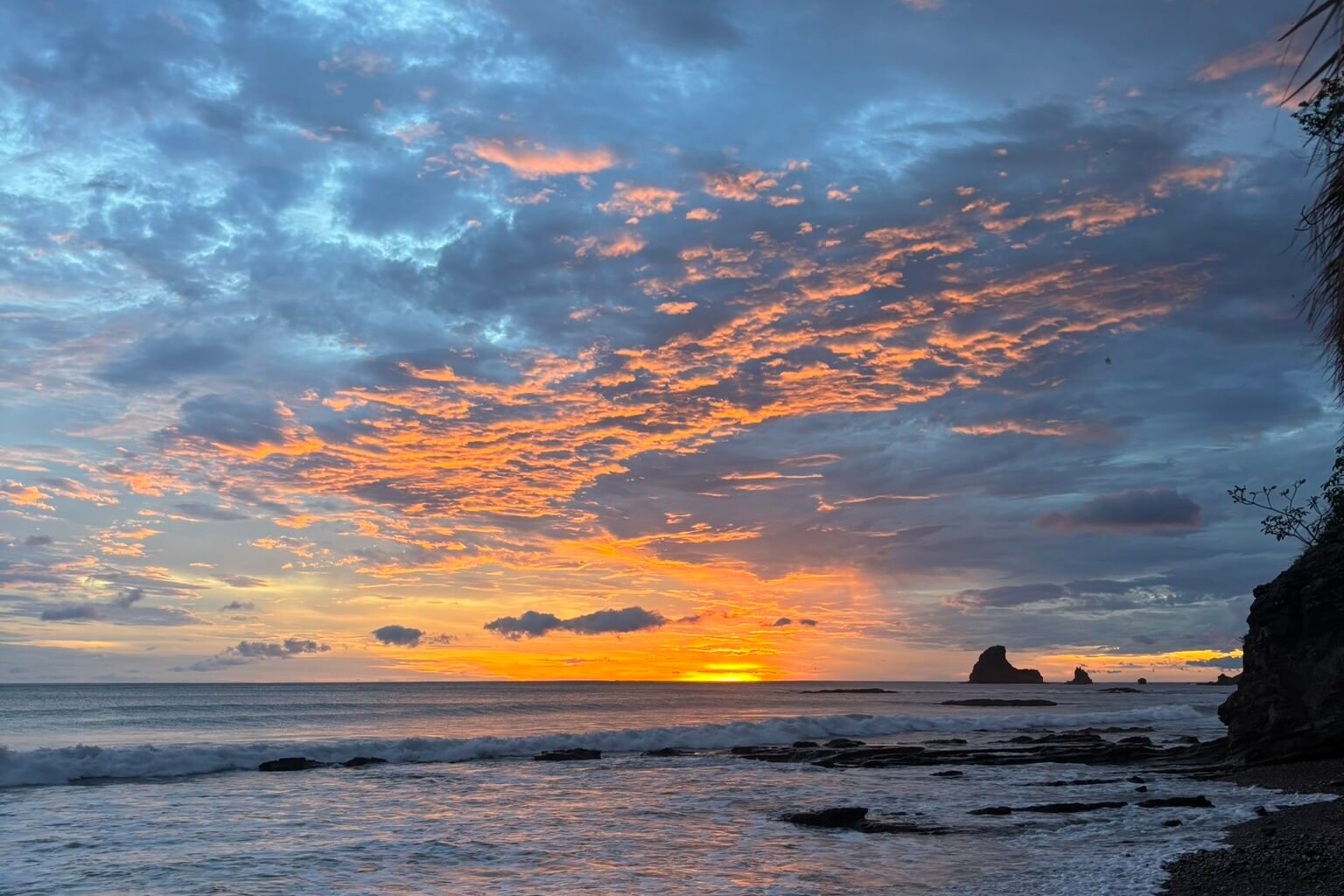 Cloudy sunset at Maderas Beach with sharkfin rock formation on horizon